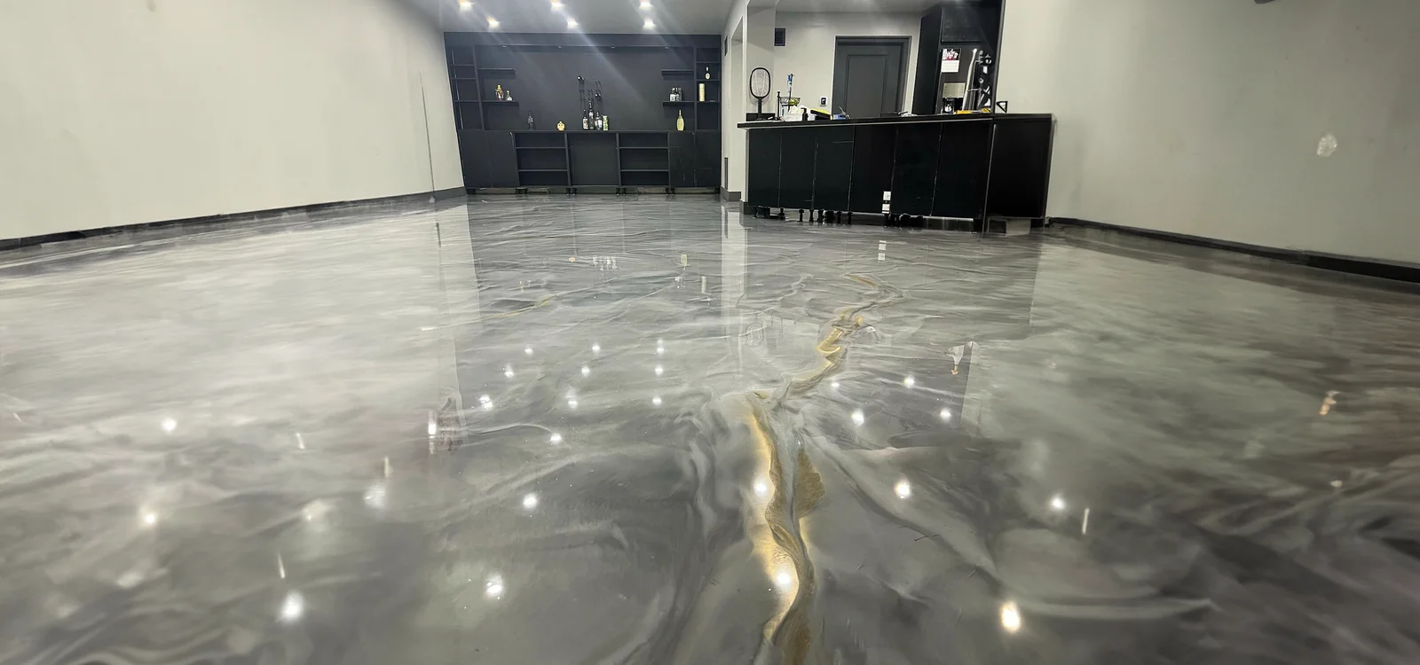 Piso epoxy metálico oscuro en bar residencial