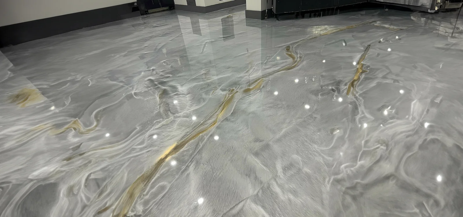 Detalle de piso epoxy metálico gris con vetas doradas